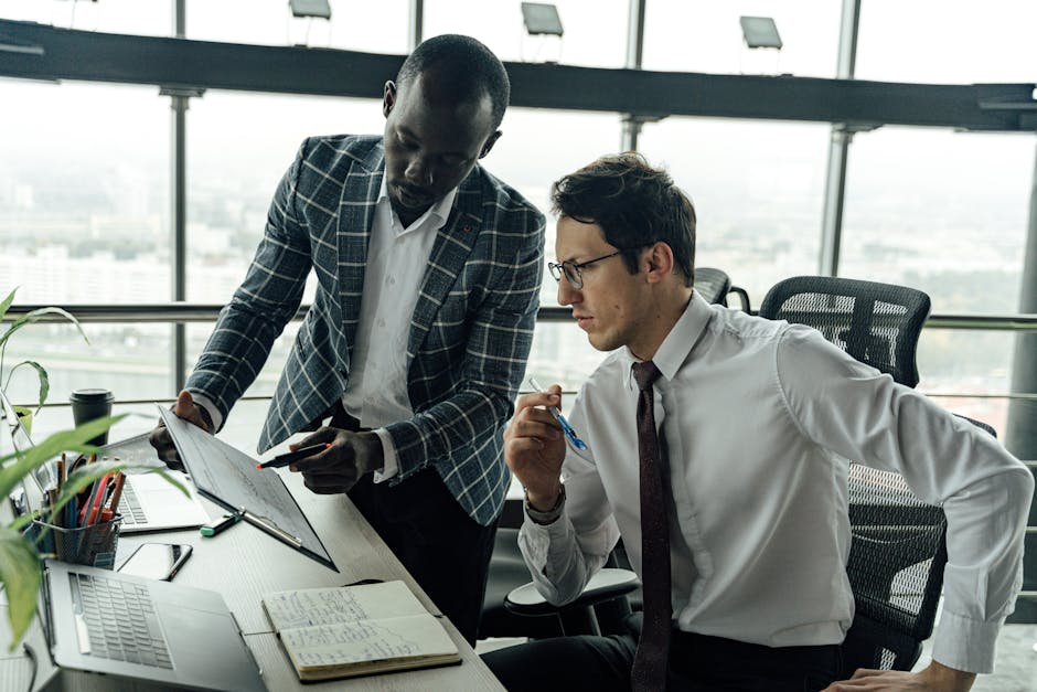 Two businessmen collaborate in a modern office setting, engaged in a focused discussion.